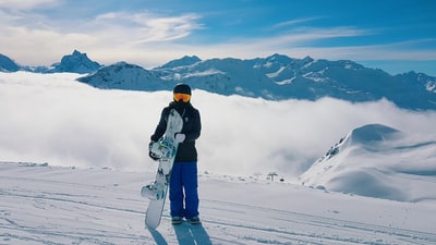 男人带着滑雪板站在白雪覆盖的山
